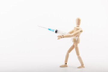 wooden mannequin with syringe against white background