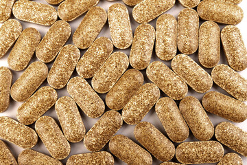 Nutrition supplements, brown vitamin pills on white background.