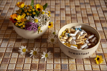 A ceramic bowl with medicinal herbs and a bowl with various pills and tablets are on the countertop.