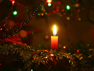 Red candle burning on the Christmas tree background.