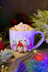 Warm holiday setting with a vibrant mug overflowing with marshmallows, set amidst twinkling lights, wintery greenery, and classic festive ornaments.