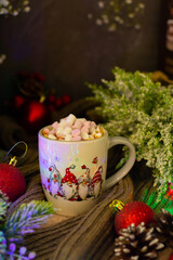 Obraz na płótnie Canvas Enchanting holiday setup featuring a mug filled with hot cocoa and marshmallows, adorned with festive chicken illustrations, surrounded by wintery flora and baubles.