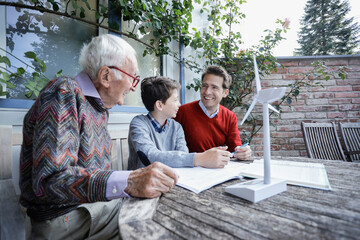 Smiling man looking at father by son studying in backyard