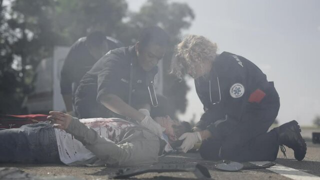 Team of paramedics rescuing wounded asian man