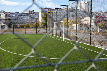 Lawn field for playing football behind the green fence mesh. Close-up of soccer field with green grass