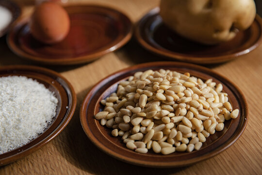 Pine nuts in plate with panellets ingredients on table