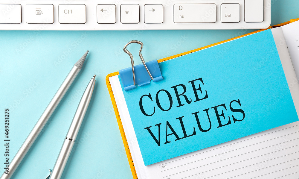 Aufkleber core values text on sticker on the blue background with pen and keyboard