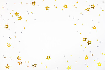 Shiny confetti of gold and silver color on a white background. Festive background. Frame, flat lay, top view, copy space.