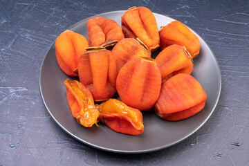 Dried persimmon in wooden plate on black plate, Dried persimmon on a black table background.
