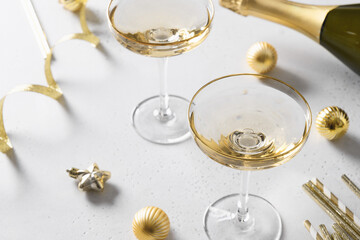 New Year champagne and Christmas gold baubles on white background. Festive holiday greeting card. Close up.