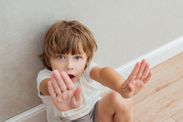 Concept of domestic violence and child abuse.Little boy showing STOP gesture with his hand