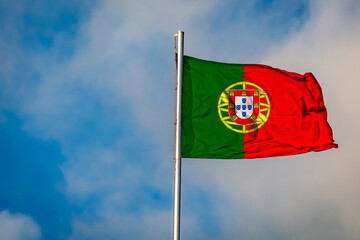 A Flag of Portugal flying on a Flagpole against the Sky