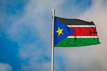 A Flag of South Sudan flying on a Flagpole against the Sky