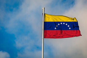 A Flag of Venezuela flying on a Flagpole against the Sky