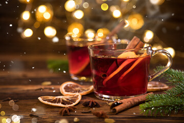 Christmas mulled red wine with spices and fruits on old wooden table. Traditional hot drink at...