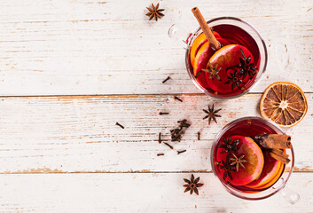 Christmas mulled red wine with spices and fruits on old wooden table. Traditional hot drink at...