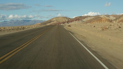 Road trip to Death Valley, Artists Palette drive, California USA. Hitchhiking auto traveling in America. Highway, colorful bare mountains and arid climate wilderness. View from car. Journey to Nevada.