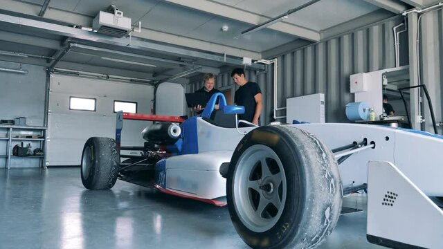 Workshop employees are checking a racing car