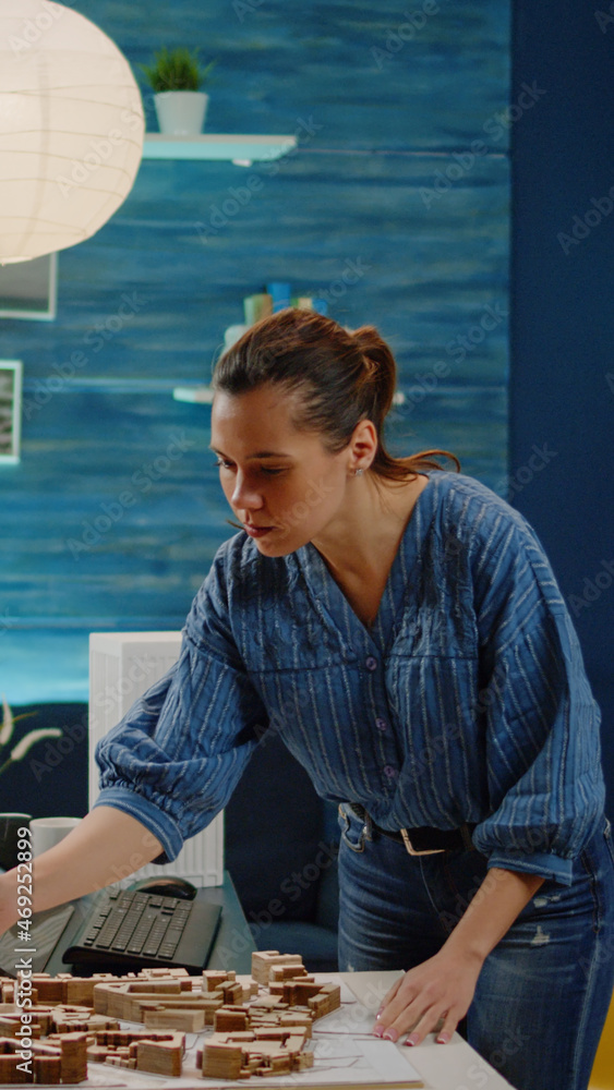 Poster woman architect checking blueprints and maquette analyzing model for construction layout of modern b