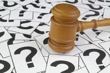 Judge's gavel on question marks background.	