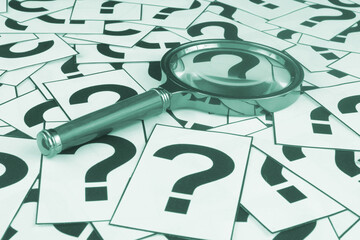 Review questions concept. Magnifying glass on question marks background.