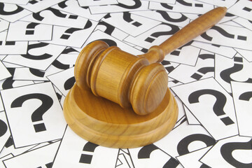 Legal questions and answers concept. Wooden judge gavel on question marks background.	