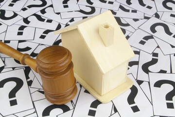 Judge gavel with house on question marks background.	Real estate property and law concept.