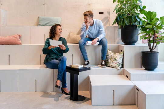 Businesswoman Discussing Over Tablet PC With Colleague In Office