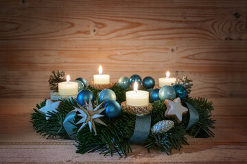Advent wreath with four lit candles, blue turquoise Christmas baubles and festive decoration on warm rustic wood, copy space, selected focus - Powered by Adobe
