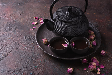 Obraz na płótnie Canvas Black japanese cast iron teapot with tea of dry roses