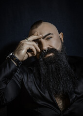 Handsome man with a black beard in a black shirt looks thoughtfully