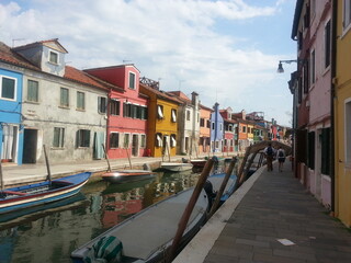 Fototapeta na wymiar l'île aux maisons colorés, l'île Burano, en Italie, petite commune avec des anciennes habitations très colorées et vivantes, avec son petit ruisseau de bateaux comme Venise, coin très touristique