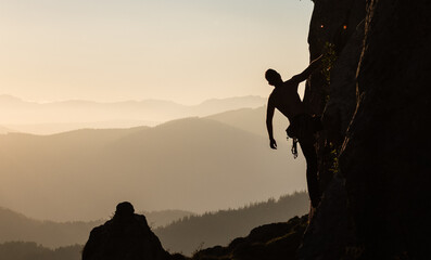 joven escalando al atardecer con las monta&ntilde;as de fondo