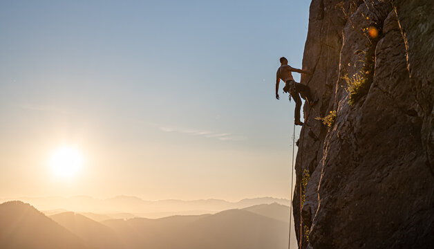joven escalando al atardecer con las monta&ntilde;as de fondo