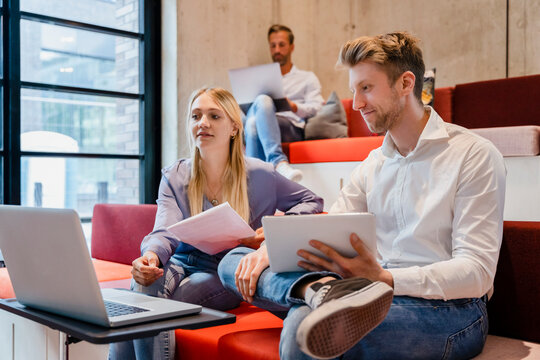 Young coworkers using laptop at desk