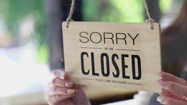 The business owner is walking to close the sign hanging in the shop to close customer service. After the corona virus situation began to spread heavily.