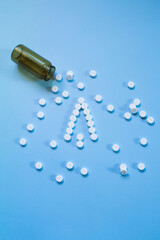 Naklejka premium White medical pills and tablets spilling out of a drug bottle on a blue background. Christmas theme, pills like a Christmas tree. So boxes as an arrow