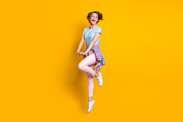 Fototapeta na wymiar Full length body size view of lovely cheerful girl jumping having fun posing good mood isolated over bright yellow color background