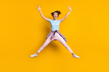 Fototapeta na wymiar Photo portrait full body view of woman spreading arms legs with tight waist shirt jumping up isolated on vivid yellow colored background