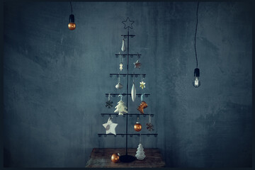 New Year Christmas card. Christmas tree with wooden and metal decorations on the background of a concrete wall in an industrial and loft style.