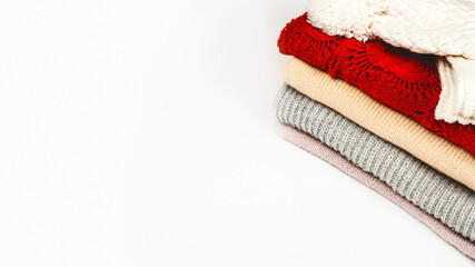 Stack of clean freshly laundered, neatly folded women's clothes. Pile of sweaters on the table, white background. Copy space, close up, top view.