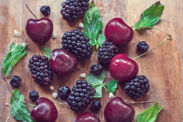 Blacberry, cherry and  blueberries with green mints on a wooden table, close up