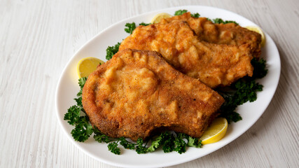 Homemade Fried Pork Chops on a White Plate, side view.