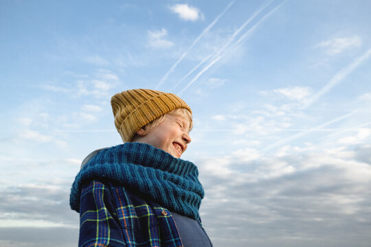 Happy boy wearing scarf under cloudy sky