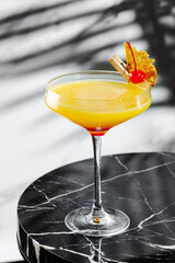 citrus and pineapple cocktail on marble table close up. tropical cocktail with shadow of tropical plants branch on background