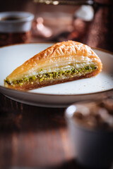 Turkish or Bosnian dessert called Baklava with pistachio served with traditional Turkish or Bosnian coffee set on a wooden board in moody atmosphere