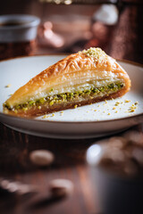 Turkish or Bosnian dessert called Baklava with pistachio served with traditional Turkish or Bosnian coffee set on a wooden board in moody atmosphere