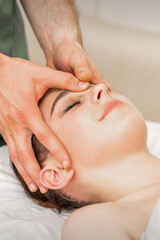 Fototapeta na wymiar Pretty young caucasian woman receiving a head massage by a male massage therapist in a beauty salon
