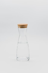 glass carafe with fresh water and cork lid on top on a white background