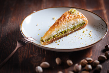 Turkish or Bosnian dessert called Baklava with pistachio served with traditional Turkish or Bosnian coffee set on a wooden board in moody atmosphere